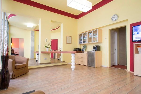 Heller und moderner Wartebereich mit Holzboden, Kaffeeautomat und gemütlichen Sesseln.